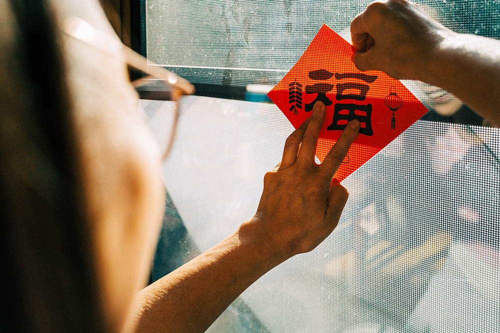 Image of a person putting up Chinese New Year decor on their window
