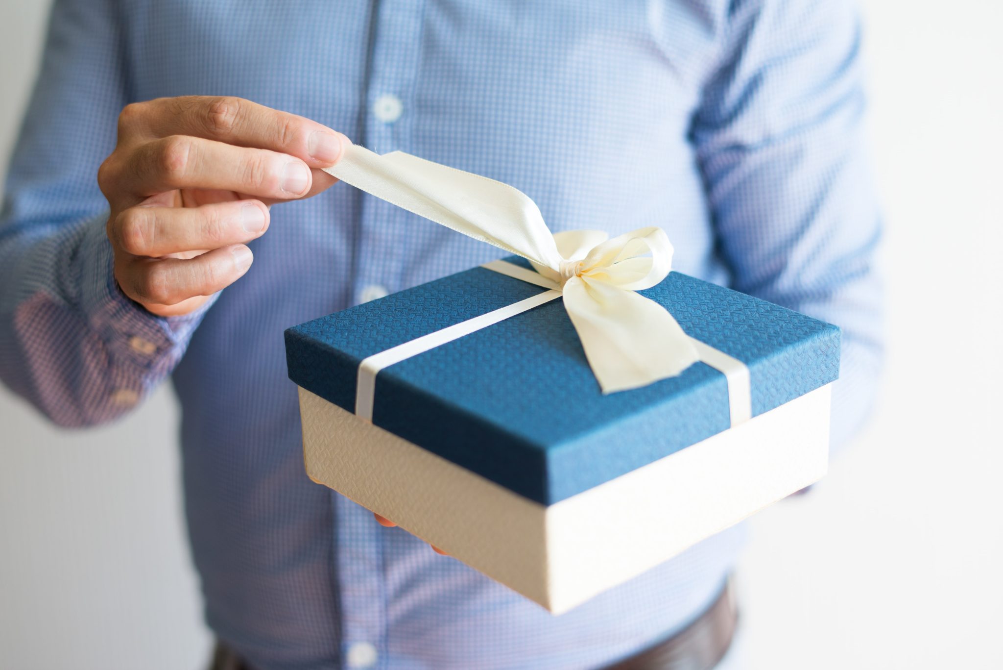 Close-up of a staff opening a nicely packaged corporate gift